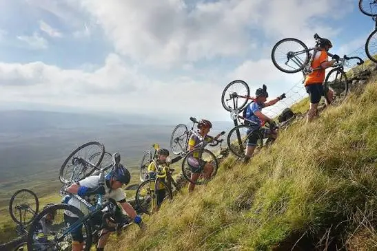 Riders carrying bikes up a 3 Peaks climb